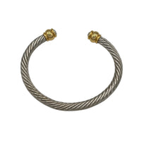 Close up view of Vintage silver twisted cable open cuff bracelet with gold and rhinestone ends displayed on black pillow white background.