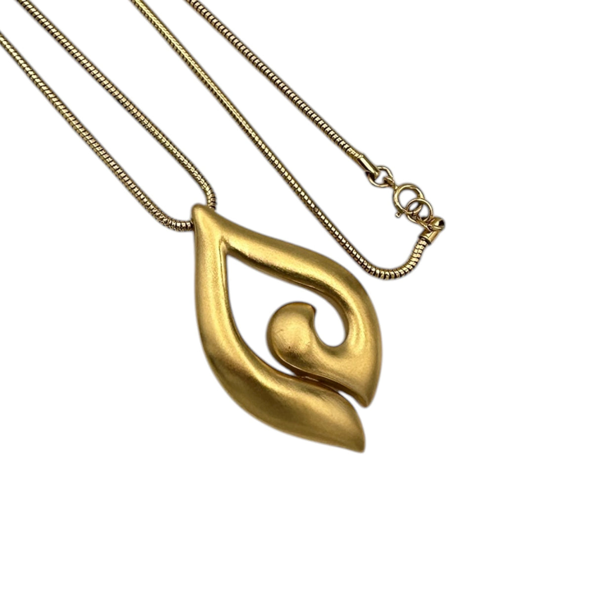 Close up view of the pendant of Vintage Trifari gold modernist pendant necklace on long snake chain on white background.