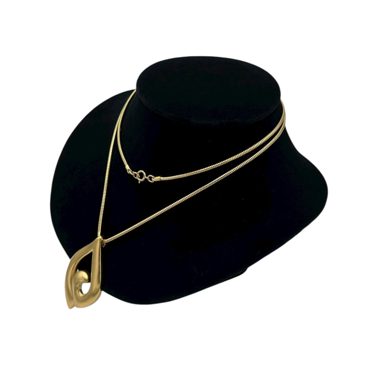 Side view of Vintage Trifari gold modernist pendant necklace on long snake chain on black bust.
