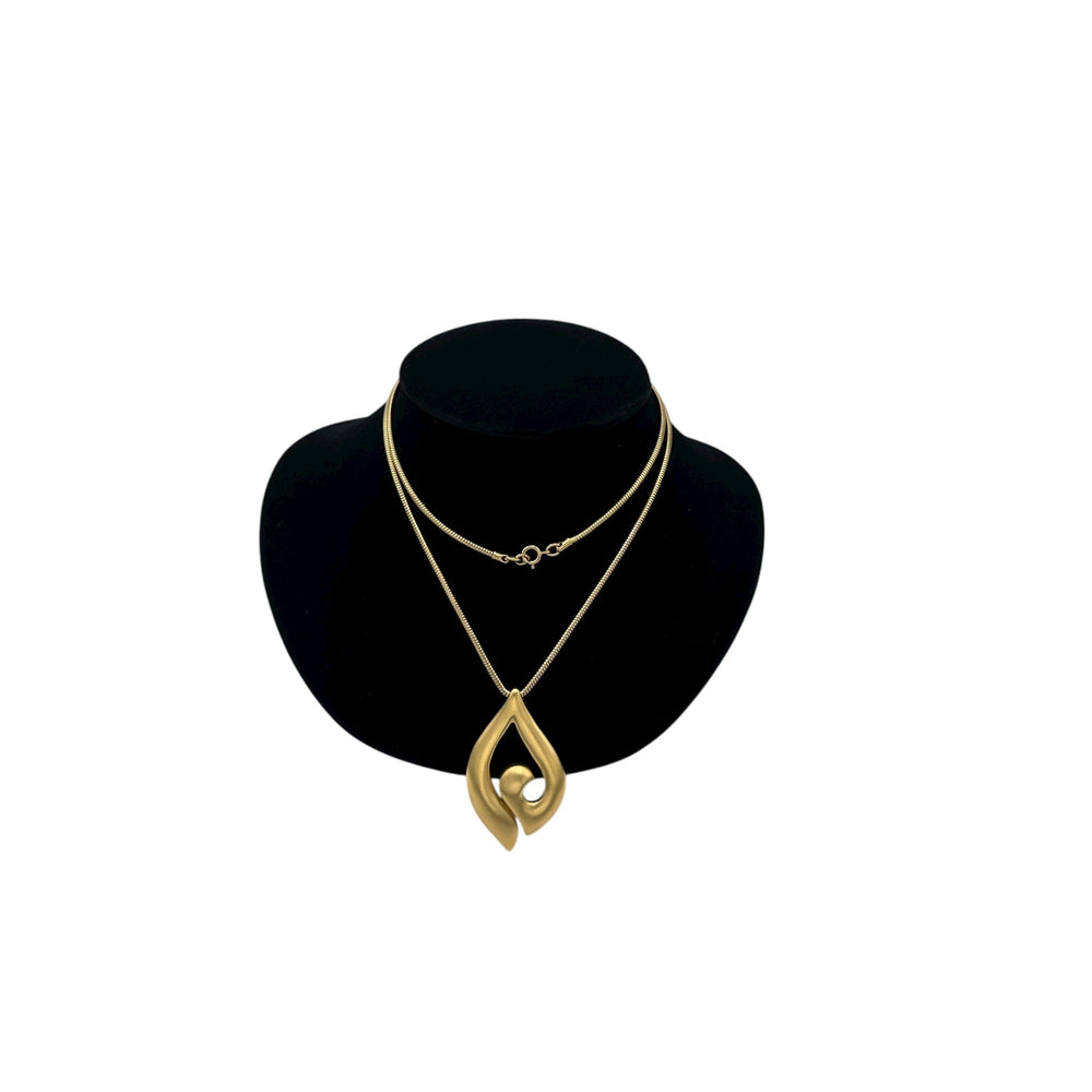 Vintage Trifari gold modernist pendant necklace on long snake chain on black bust.