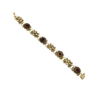Close up view of Vintage Victorian Revival gold tone book chain bracelet with ruby red glass cabochon centerpiece displayed on white background.