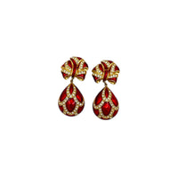 Close up view of Whiting & Davis vintage red enamel bow and teardrop rhinestone dangle clip-on earrings, gold-tone statement jewelry on white background.